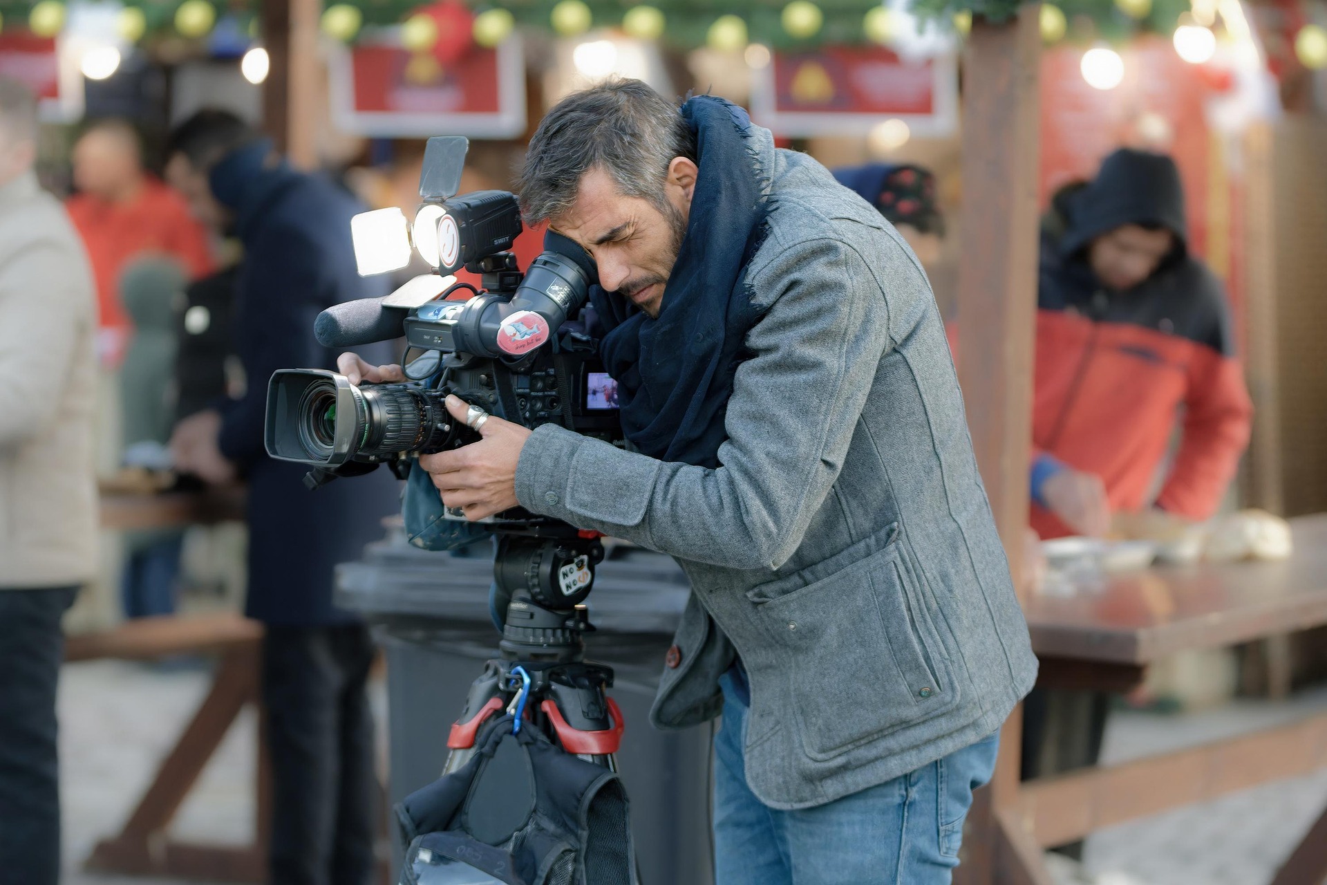 A camera operator filming with a broadcast camera at an outdoor event